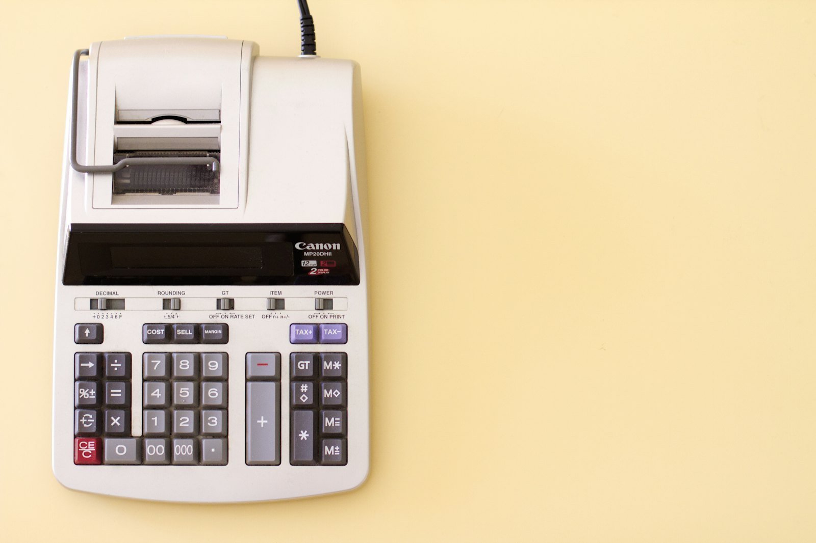 Tax forms, a phone calculator and a coffee cup arranged for year-end accounting