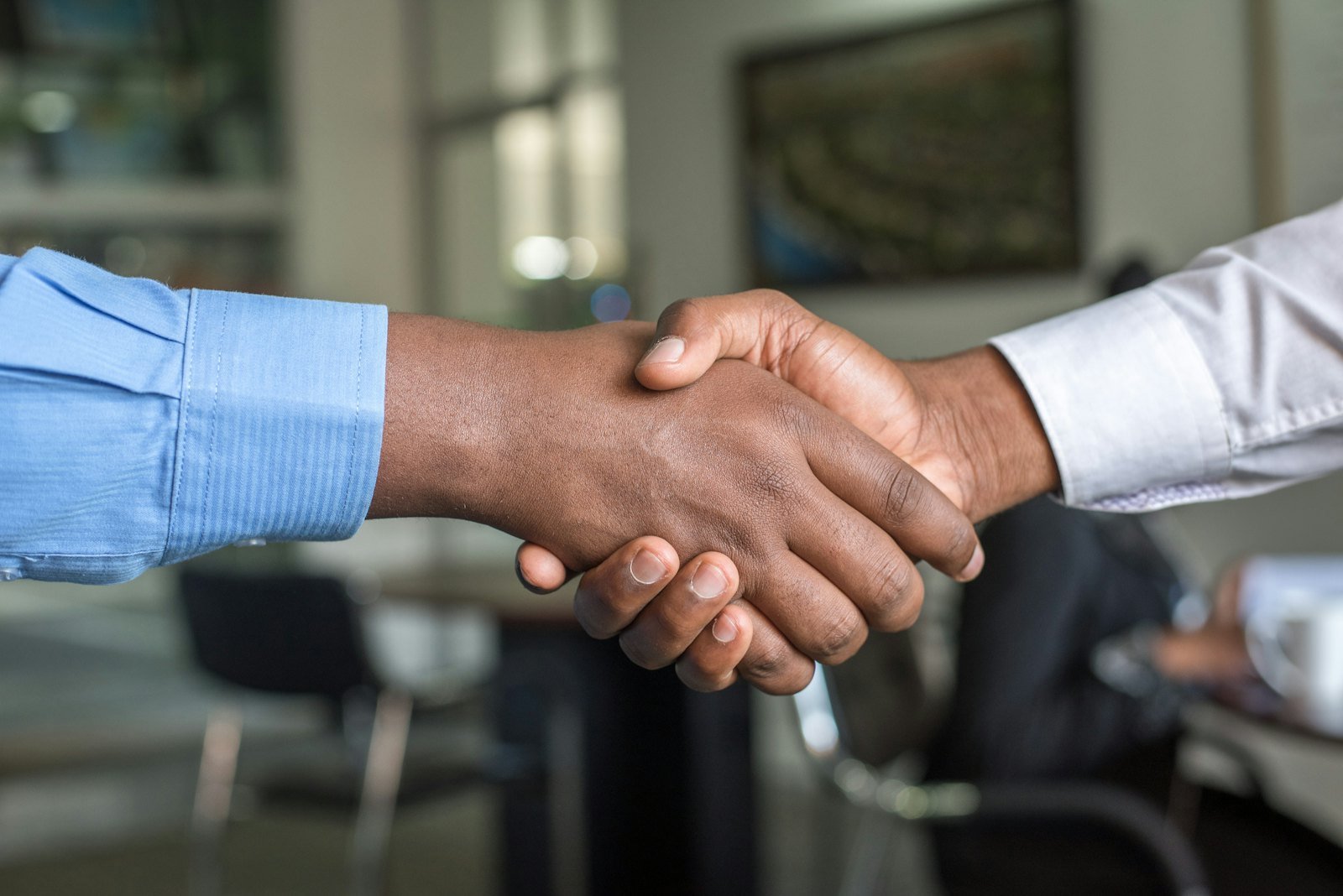 Two people shaking hands across a desk to begin working together